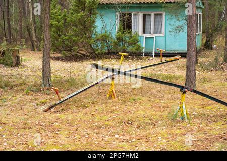 Une vieille balançoire pour enfants en ruine dans une station de vacances abandonnée et oubliée dans la forêt. Urbex. Banque D'Images