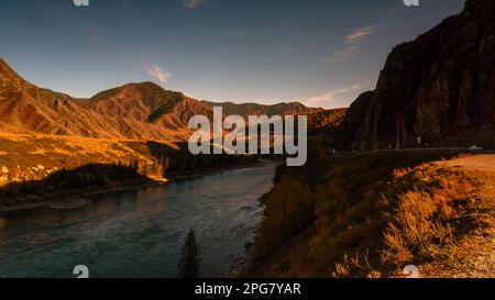 La route de montagne Chuisky Trakt va sous un rocher à l'ombre près de la rivière Katun en Altaï en automne en Sibérie. Banque D'Images