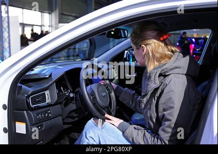 Jeune femme conducteur assis dans la cabine d'une voiture électrique, main tenant le volant. Plug-in d'exposition en Ukraine. 2 mars 2018. Kiev, Ukraine Banque D'Images