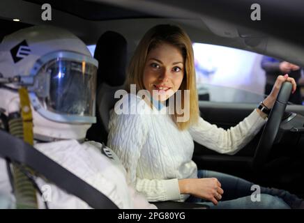 Jeune femme conducteur assis dans la cabine d'une voiture électrique, main tenant le volant. Plug-in d'exposition en Ukraine. 2 mars 2018. Kiev, Ukraine Banque D'Images