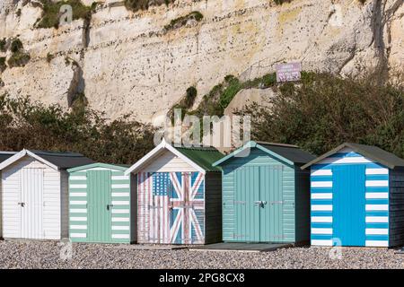 Rangée de 5 cinq cabanes de plage à la base des falaises de Beer Beach, Seaton, Devon UK en mars Banque D'Images