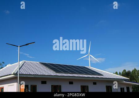 Panneaux solaires sur le toit et il y a aussi des éoliennes autour. Le concept des ressources renouvelables et durables. Banque D'Images