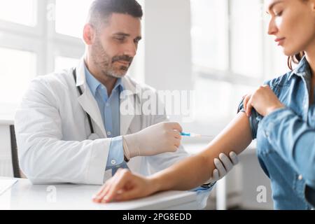 Jeune femme se vaccine contre le coronavirus, médecin masculin faisant l'injection dans l'épaule pour la patiente Banque D'Images