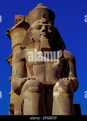 Ozymandias, roi des rois : Assis statue du « grand ancêtre » de l'Égypte, le pharaon Ramsès II, longtemps au pouvoir, de la dynastie du Nouveau Royaume de 19th (régné de 1279-1213 av. J.-C.), à l'entrée de la cour peristyle ou colonisée du Temple de Louxor, au milieu des ruines de l'ancienne capitale de Thèbes, sur la rive est du Nil. Banque D'Images