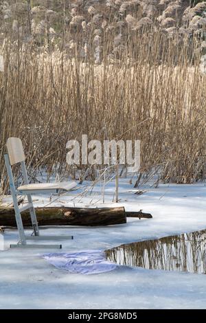 photo d'une chaise debout sur un lac près d'un trou dans la glace pendant la journée Banque D'Images