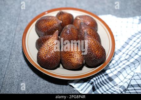 Salak ou fruit de serpent isolé. Salak Palm , renoncez ou serpent fruits dans un plat en bois sur la table Banque D'Images