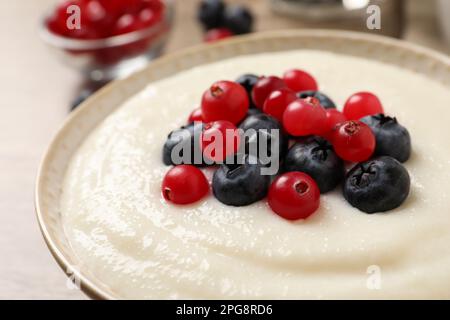 Délicieux pudding de semoule avec des baies dans un bol sur la table, en gros plan Banque D'Images