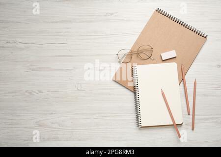 Carnets, crayons, lunettes et gomme sur table en bois blanc. Espace pour le texte Banque D'Images