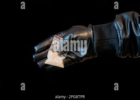 Main du Mans tenant sur le paquet de plastique de paume avec la poudre de cocaïne ou d'autres drogues. Macro-image gros plan. le concept de trafic illicite de drogues. narcotra Banque D'Images