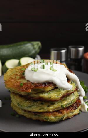 Délicieux beignets de courgettes à la crème sure sur l'assiette Banque D'Images