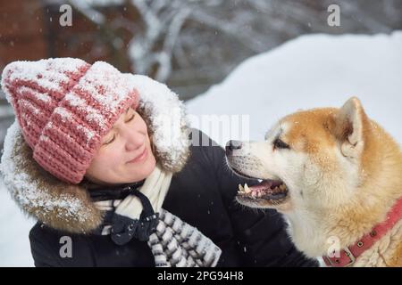 Une femme avec un chien akita. sports et loisirs de plein air par une journée d'hiver enneigée. Gros plan. Banque D'Images