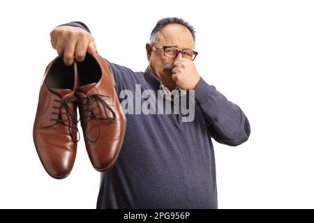 Homme mature tenant une paire de chaussures ratées isolées sur fond blanc Banque D'Images