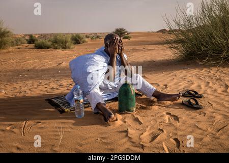 Brahim Ramdhane, ancien esclave et fondateur de son ONG Fondation Sahel, ici à la prière de Sunite dans le désert entre Nouakshott et sa ville natale de Boutilimit en Mauritanie, où il a grandi en tant qu'esclave. Il lutte contre l'esclavage, contre l'oppression de sa tribu Haratin et pour des opportunités éducatives équitables depuis qu'il s'est libéré comme adolescent. Banque D'Images