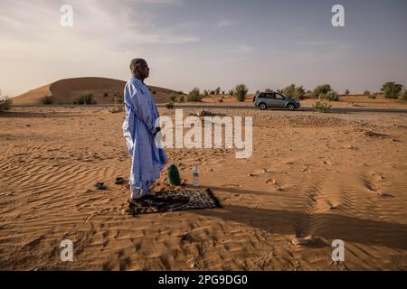 Brahim Ramdhane, ancien esclave et fondateur de son ONG Fondation Sahel, ici à la prière de Sunite dans le désert entre Nouakshott et sa ville natale de Boutilimit en Mauritanie, où il a grandi en tant qu'esclave. Il lutte contre l'esclavage, contre l'oppression de sa tribu Haratin et pour des opportunités éducatives équitables depuis qu'il s'est libéré comme adolescent. Banque D'Images