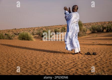 Brahim Ramdhane, ancien esclave et fondateur de son ONG Fondation Sahel, ici à la prière de Sunite dans le désert entre Nouakshott et sa ville natale de Boutilimit en Mauritanie, où il a grandi en tant qu'esclave. Il lutte contre l'esclavage, contre l'oppression de sa tribu Haratin et pour des opportunités éducatives équitables depuis qu'il s'est libéré comme adolescent. Banque D'Images