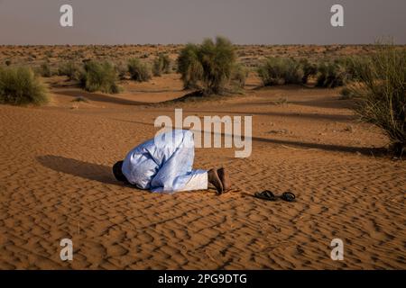 Brahim Ramdhane, ancien esclave et fondateur de son ONG Fondation Sahel, ici à la prière de Sunite dans le désert entre Nouakshott et sa ville natale de Boutilimit en Mauritanie, où il a grandi en tant qu'esclave. Il lutte contre l'esclavage, contre l'oppression de sa tribu Haratin et pour des opportunités éducatives équitables depuis qu'il s'est libéré comme adolescent. Banque D'Images