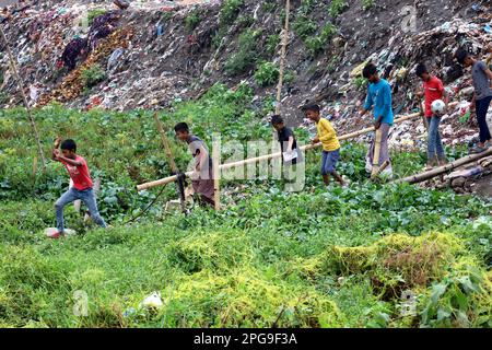 Dhaka, Dhaka, Bangladesh. 21st mars 2023. Les habitants de la région traversent un pont en bambou dans un canal de Mohammadpur, Dhaka. Des piles de déchets des deux côtés du canal polluent l'environnement et bloquent le canal. La plupart des canaux de Dhaka ont été pris en charge par le déversement des ordures de cette façon. (Credit image: © Syed Mahabubul Kader/ZUMA Press Wire) USAGE ÉDITORIAL SEULEMENT! Non destiné À un usage commercial ! Banque D'Images