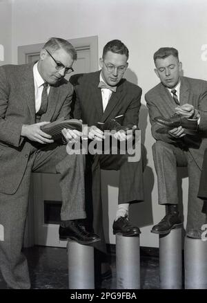 1950s, historique, trois hommes adultes adaptés, bien habillés en chemise et cravates, peut-être vendeurs, étudiant les chaussures en cuir pour hommes, une vérification de l'étiquette de prix, Eugene, Oregon, États-Unis. Banque D'Images