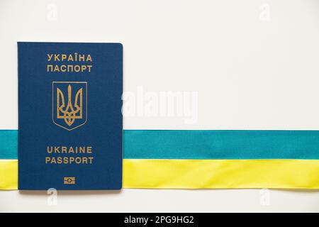 Le passeport biométrique étranger et la bande se trouvent horizontalement dans les couleurs du drapeau de l'Ukraine sur un fond blanc, passeport Banque D'Images