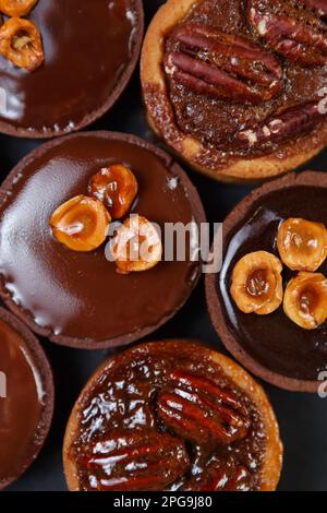 Petites tartes au chocolat sur une couche plate. Six délicieux gâteaux sablés au chocolat au lait belge et aux noix cuits dans un café de pâtisserie Banque D'Images