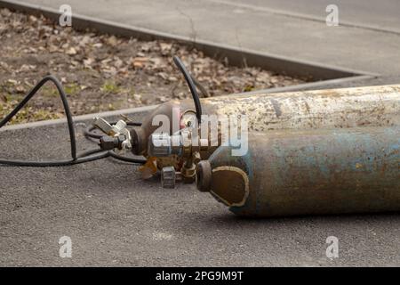 Une vieille bouteille de gaz se trouve sur la route sur la rue dans la zone de couchage de la ville, réparation Banque D'Images