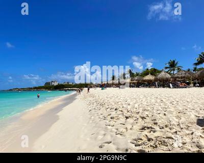 Eagle Beach, Oranjestad, Aruba - 8 mars 2022. Les gens sur la plage et dans l'eau. Des parasols et des chaises bordent la plage. Banque D'Images