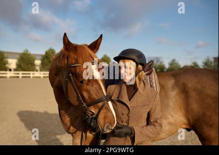 Femme pilote passant du temps avec son cheval préféré en plein air Banque D'Images