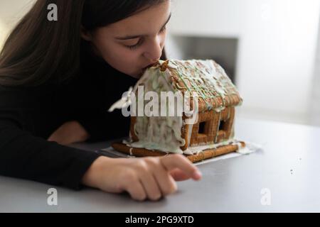 Une adolescente mange une maison de pain d'épice Banque D'Images