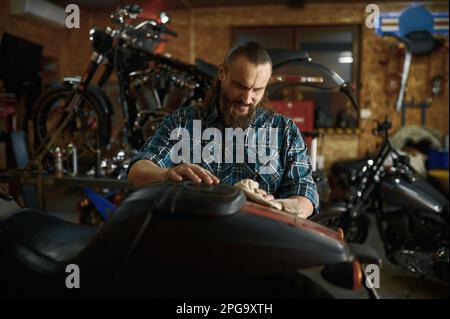 Le week-end, Biker nettoie sa moto dans un atelier de réparation Banque D'Images