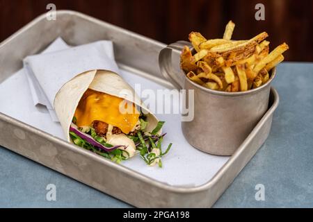 Enveloppez le rouleau de croque-monsieur shawarma frais. En-cas traditionnel du Moyen-Orient, avec un rouleau de kebab. Avec frites dans une tasse. arrière-plan en bois Banque D'Images