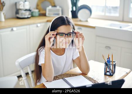 Jolie fille 12s porter des écouteurs et des lunettes faire la tâche, étudier en ligne, éprouve des problèmes de vision, des calmars, avoir la vue tombe, problèmes de santé Banque D'Images