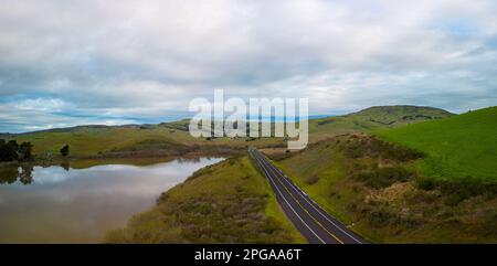 Route vide par des collines vertes et réservoir dans la belle Californie à l'aube Banque D'Images