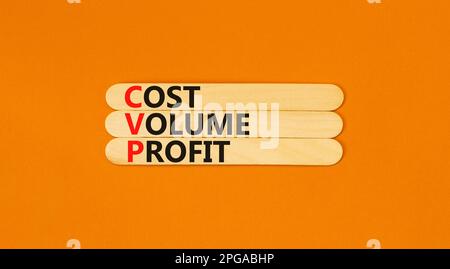 Symbole de profit de volume de coût CVP. Concept mots CVP coût volume profit sur bâton de bois sur une belle table orange fond orange. Entreprise et CVP co Banque D'Images