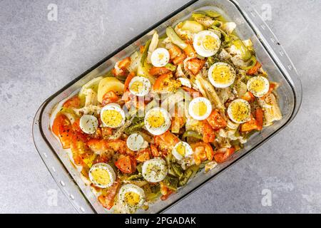 Gomes de sa morue rôtie dans de l'huile d'olive avec tomates, poivrons, oignons, œufs durs et origan. Dans un plat rectangulaire en verre. Vue de dessus. Banque D'Images