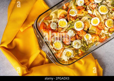 Gomes de sa morue rôtie dans de l'huile d'olive avec tomates, poivrons, oignons, œufs durs et origan. Dans un plat rectangulaire en verre de cuisson entouré d'un Banque D'Images