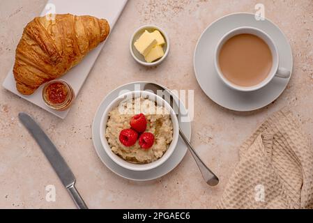 Photographie de nourriture de flocons d'avoine, avoine, porridge, petit déjeuner, croissant, thé, lait, framboises, beurre Banque D'Images