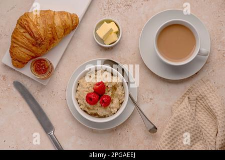 Photographie de nourriture de flocons d'avoine, avoine, porridge, petit déjeuner, croissant, thé, lait, framboises, beurre Banque D'Images