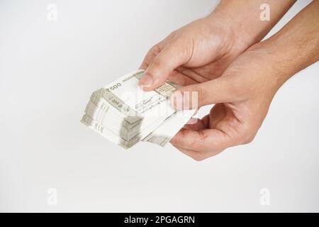 Pile d'espèces de monnaie indienne à la main sur fond blanc Banque D'Images