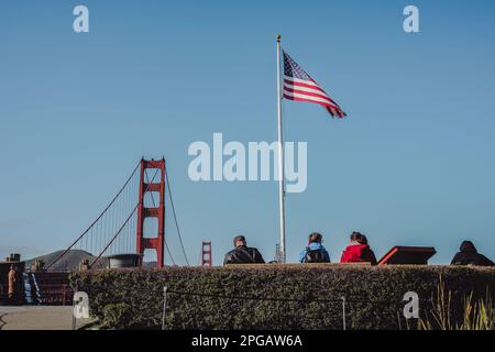 San Francisco, Californie, États-Unis. 20th mars 2023. Un groupe de touristes prend une photo avec le Golden Gate Bridge en arrière-plan, et le drapeau de la nation américaine clairement montré en arrière-plan. Le célèbre Golden Gate Bridge, l'un des monuments les plus reconnaissables des États-Unis. Le pont, qui traverse le détroit du Golden Gate et relie San Francisco au comté de Marin, est une merveille d'ingénierie depuis son achèvement en 1937. Le Golden Gate Bridge est devenu un symbole de San Francisco et une destination touristique populaire, attirant des millions de visiteurs chaque année. Le pont n'est pas activé Banque D'Images