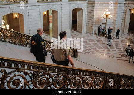 Californie, San Francisco, États-Unis. 20th mars 2023. Un shérif descend le grand escalier de l'hôtel de ville de San Francisco, entouré par la magnifique architecture des Beaux-Arts du bâtiment. Le shérif porte son uniforme et une expression sérieuse, et il est accompagné d'un collègue. Après deux ans de rénovations, l'hôtel de ville emblématique de San Francisco a enfin rouvert ses portes au public depuis juin 2021. Le projet de $550 millions visait à restaurer les éléments historiques du bâtiment tout en le modernisant pour répondre aux besoins du 21st siècle. Le projet consistait à restaurer le Banque D'Images