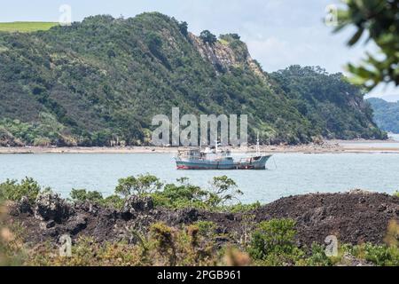 Un navire dans la baie d'Islington entre Rangitoto et l'île de Motutapu, vu du côté volcanique de Rangitoto en Nouvelle-Zélande. Banque D'Images