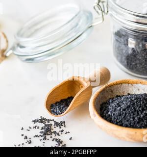 Sel de roche hawaïen noir dans un pot, un bol et une petite cuillère en bois. Banque D'Images