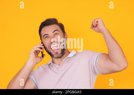 Homme enthousiaste utilisant un smartphone, bavardant, faisant un post sur les réseaux sociaux. Guy appel sur le téléphone isolé sur l'arrière-plan du studio. Blogueur parlant au téléphone Banque D'Images