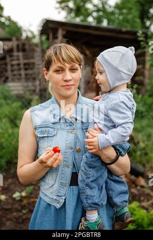 Maman et son fils ayant le temps de manger. Mère donnant des fraises à son fils Banque D'Images