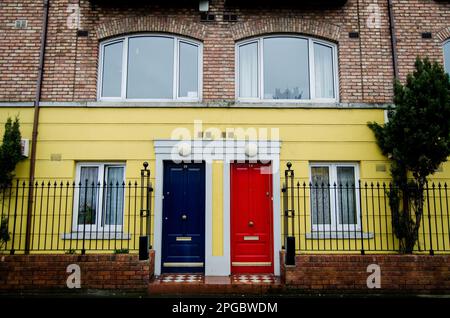 Une maison de deux étages avec deux portes aux couleurs vives en rouge et bleu Banque D'Images