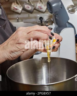 Le chef fend un œuf dans un plat qui est préparé dans un bol Banque D'Images