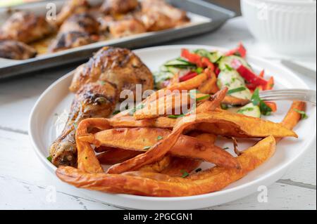 Frites de patate douce avec poulet et salade sur une assiette Banque D'Images