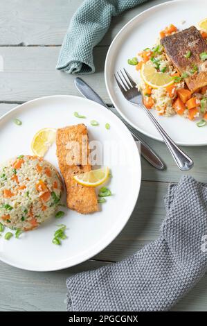 Faire revenir le filet de saumon frit avec du riz brun et des légumes sur des assiettes avec deux variantes de service Banque D'Images