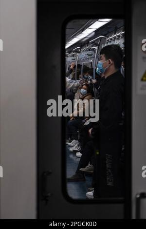 Un cliché vertical de personnes portant un masque facial sur un métro public bondé Banque D'Images