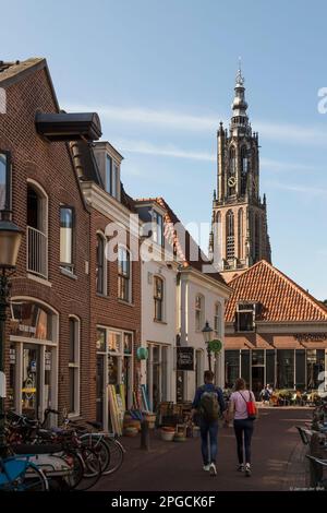 Jeune couple marche main dans la main à travers une rue étroite confortable à travers le centre d'Amersfoort. Banque D'Images